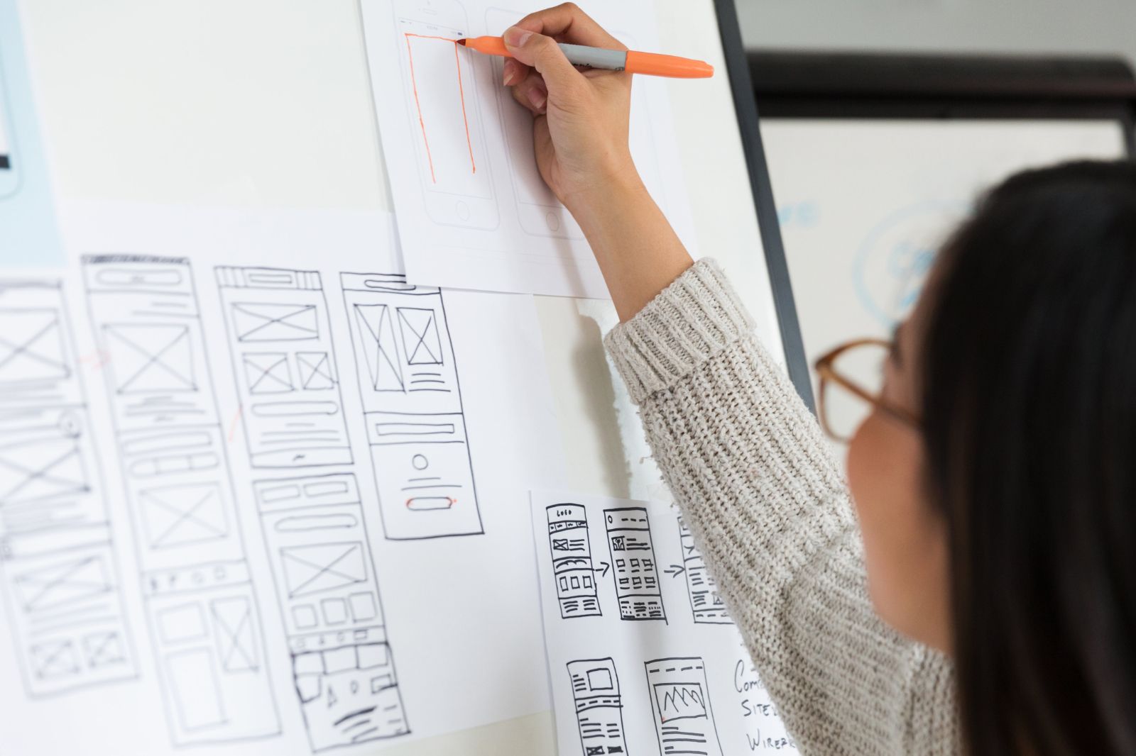 Woman drawing user interface layouts and wireframes on a whiteboard